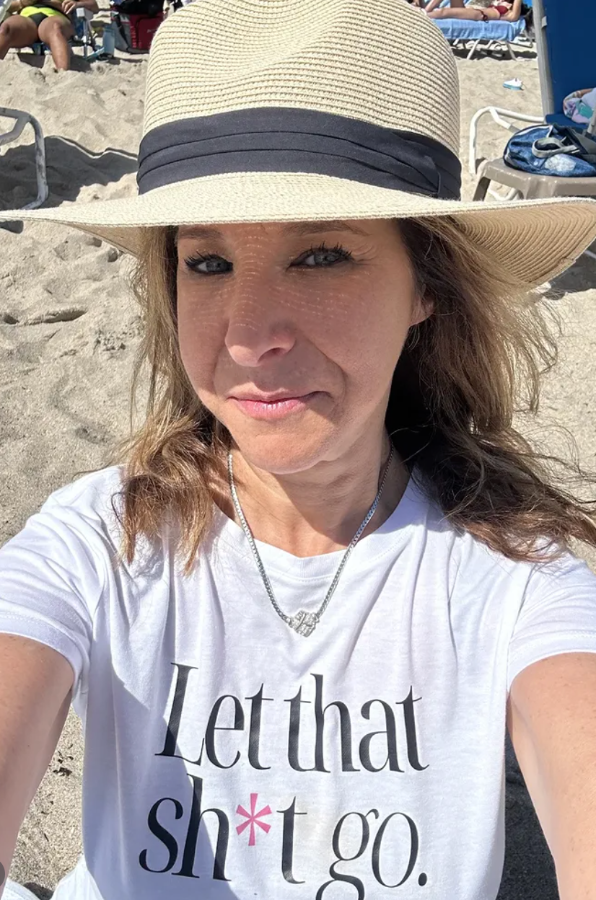 Person wearing a straw hat and white t-shirt with text on a beach